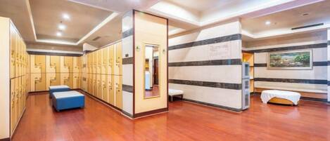A hotel lobby with wooden flooring, a seating area, and a row of lockers.