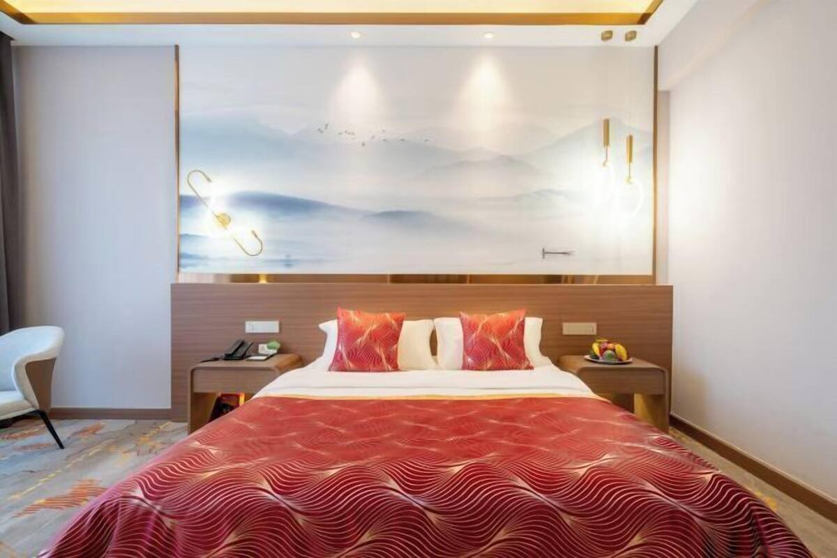 Une chambre d’hôtel avec un grand lit, une table de chevet avec un téléphone et une œuvre d’art accrochée au mur.