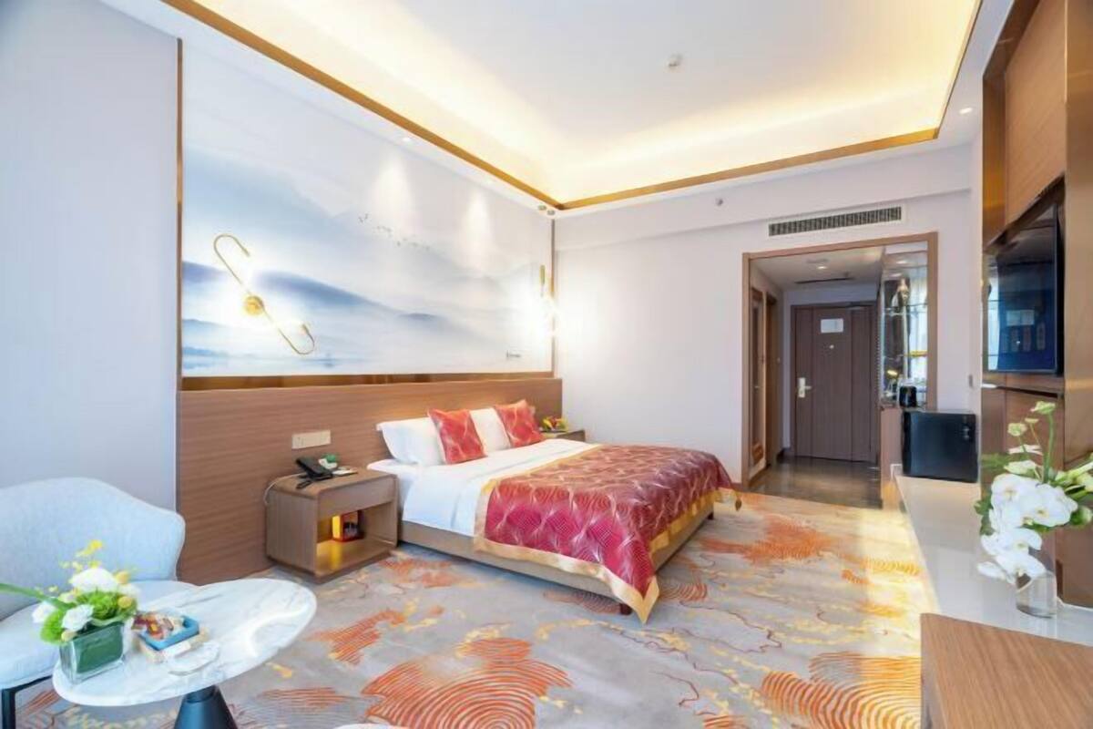 Une chambre d’hôtel avec un lit, une table de chevet, une lampe et une vue sur le couloir.