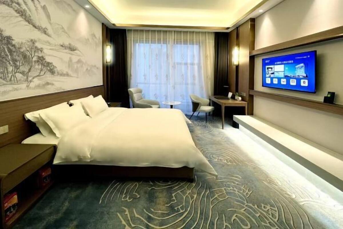Une chambre d’hôtel avec un grand lit, un téléviseur fixé au mur, un bureau et une chaise.