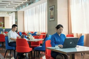 A dining area with tables and chairs, some occupied by individuals using laptops. - Montriche International Hotel (WEIFANG)