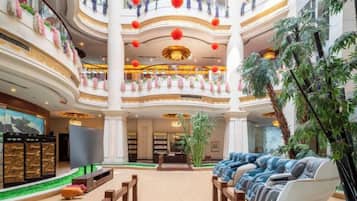 A multi-level atrium with a central seating area, balconies, and indoor plants.