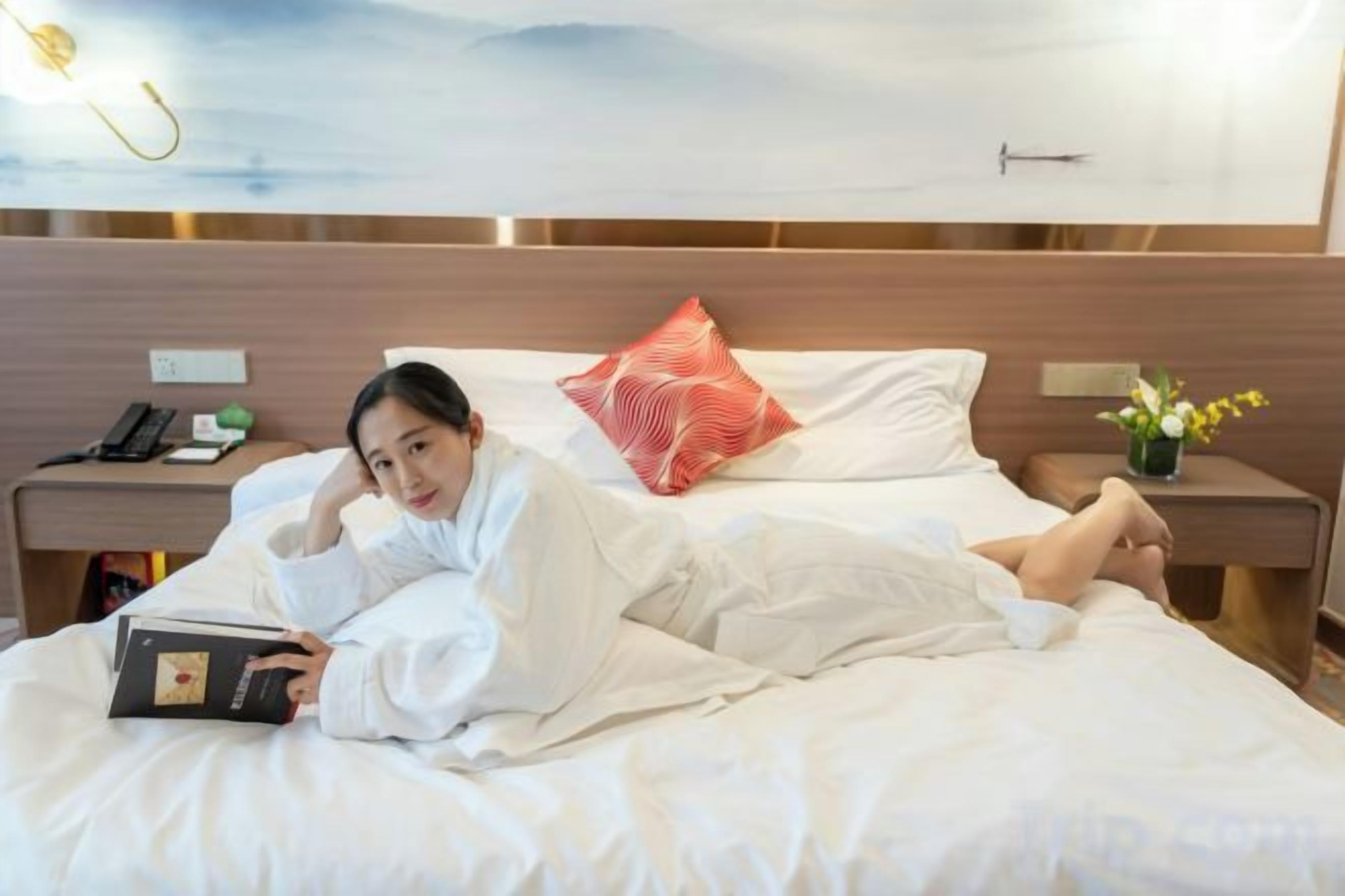 A hotel room with a bed, a bedside table with a lamp, and a nightstand with a phone.