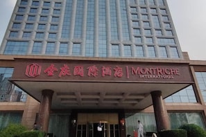 A hotel entrance with a sign for 'Montriche International' and a tall building in the background. - Montriche International Hotel (WEIFANG)