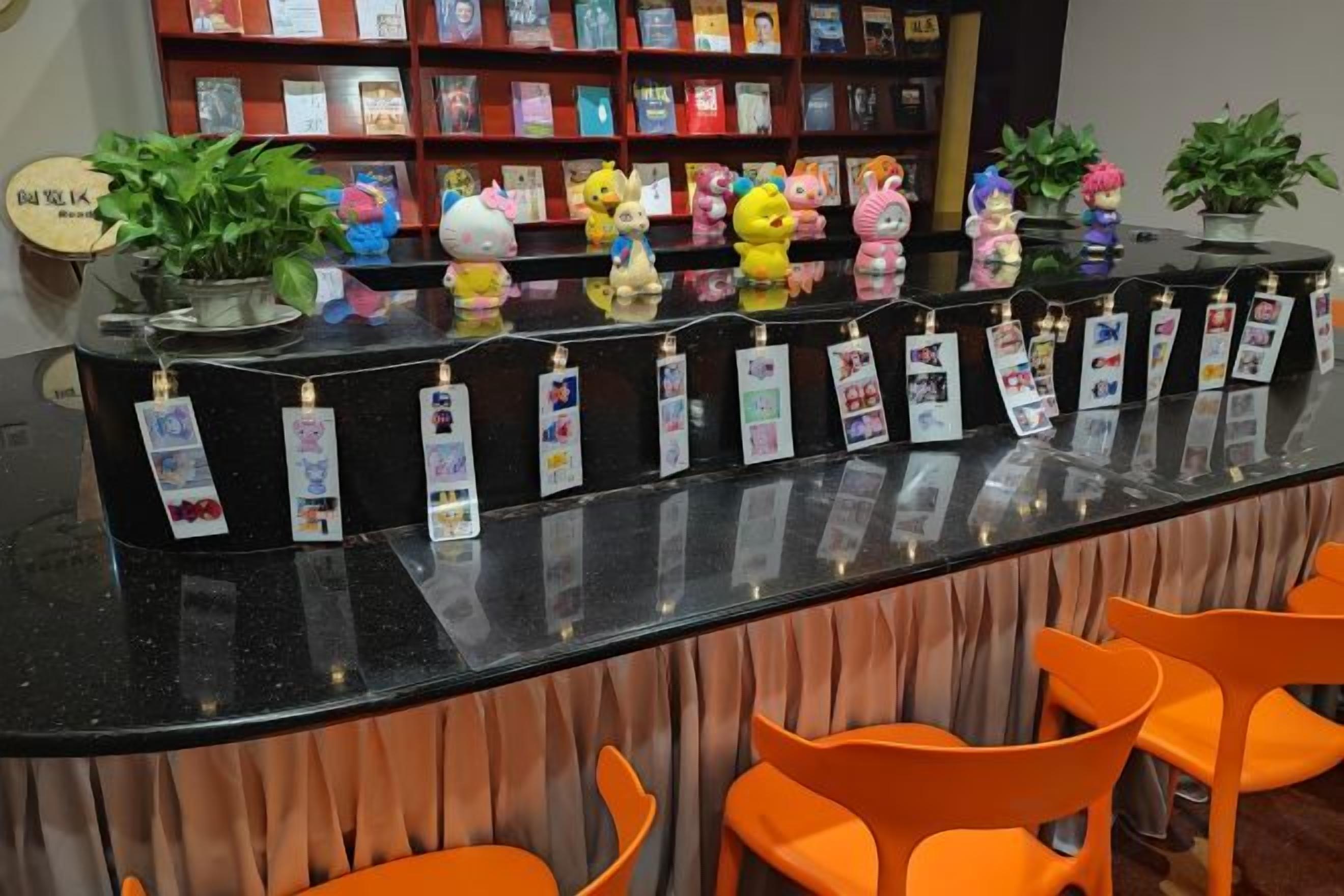 A reception desk with a black countertop, orange chairs, and a bookshelf in the background.