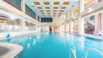 An indoor swimming pool with clear lanes, a diving board, and a view of the ceiling.