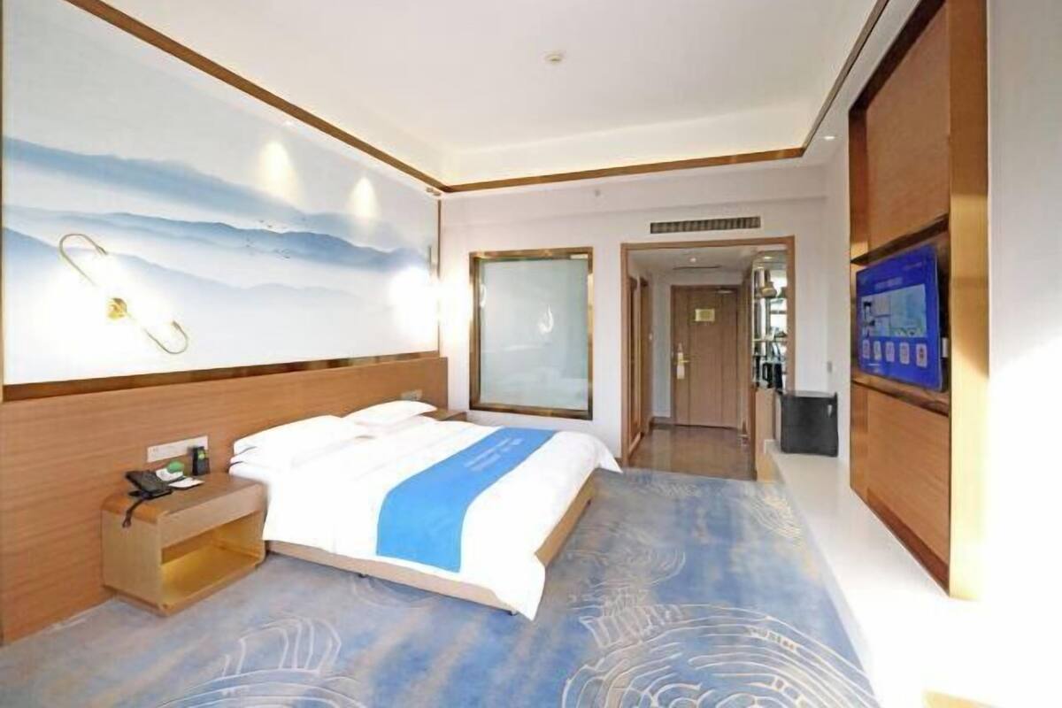 Une chambre d’hôtel avec un lit, une table de chevet, une télévision et une grande fenêtre.