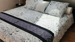 A bedroom with a skylight, a bed with floral bedding, a bedside table, and a lamp. - TI BIHAN housing >> (Bénodet,)