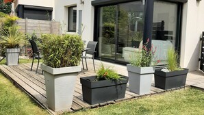 A modern house with a large glass door, a deck, and potted plants. - TI BIHAN housing >> (Bénodet,)
