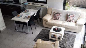 A modern living room with a sofa, a coffee table, and a dining area with chairs. - TI BIHAN housing >> (Bénodet,)