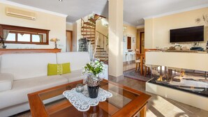A modern living room with a sofa, coffee table, and a fireplace. There is a dining area with a table and chairs, and a staircase leading to another level. - *****Fewo Mariposa - luxury beach penthouse 200sqm, great sea view, free garage (Guardamar)