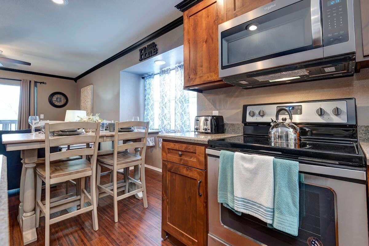 A compact kitchen with wooden cabinets, a microwave, a stove, and a dining area with a table and chairs.
