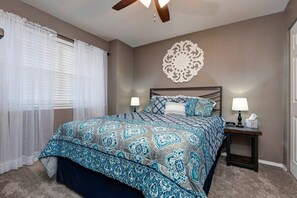 A bedroom with a bed, two bedside tables with lamps, a ceiling fan, a decorative wall piece, and sheer curtains. - 19-4 Bluebird Nest Closest to SDC w/ Indoor/Outdoor Pools & Splash Pads (Branson)