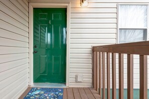 Une porte verte avec un paillasson sur lequel on peut lire : « Bienvenue, votre hôte. »