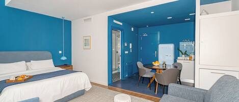 Una habitación de hotel moderna con cama, zona de estar con mesa y kitchenette.