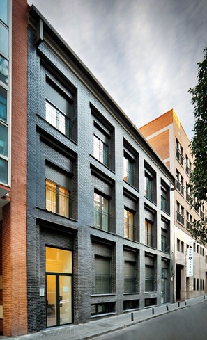 Un edificio moderno con fachada de ladrillo, ventanas amplias y una entrada visible.