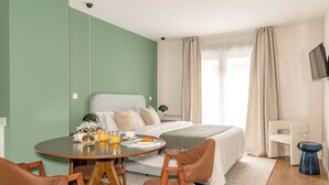 Ein modernes Hotelzimmer mit einem Bett, einem runden Esstisch und zwei Stühlen.