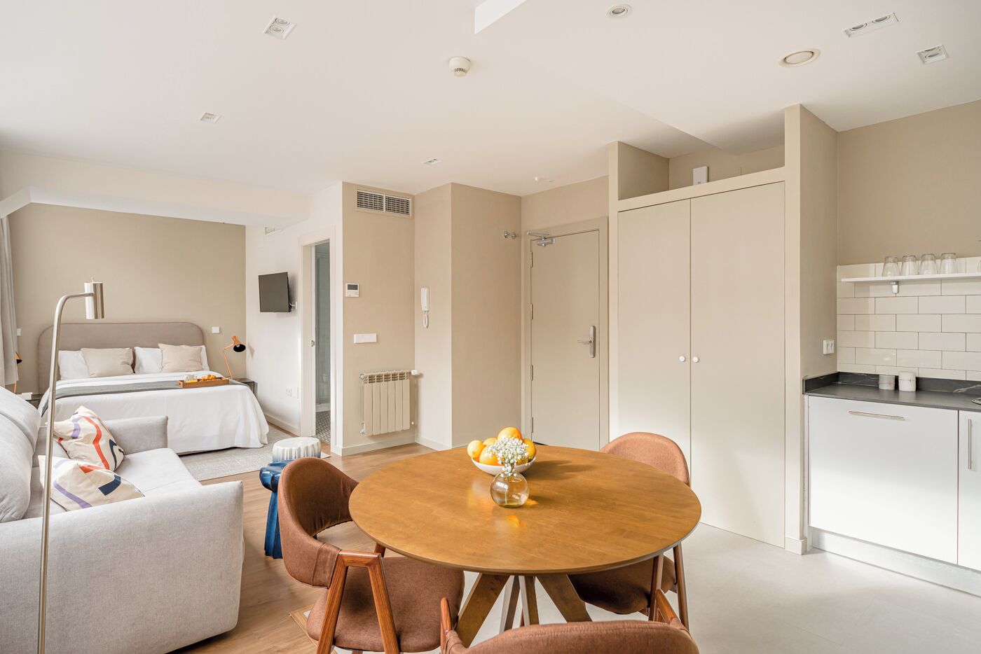 Ein modernes Hotelzimmer mit Bett, Sofa, Esstisch und einer Küchenzeile.
