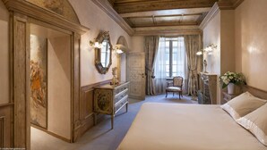 A classic bedroom with a large bed, a dresser, a chair, and a mirror.