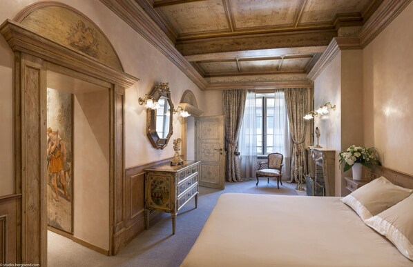 A classic bedroom with a large bed, a dresser, a chair, and a mirror.