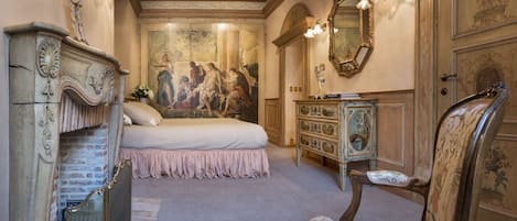 A bedroom with a large bed, a dresser, a chair, and a wall with a mural.