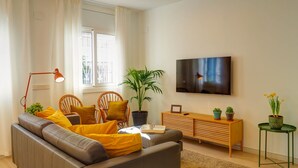 A modern living room with a sofa, a TV, a potted plant, and a wooden cabinet. - Sebastian Patio by Hello Homes Sitges (Sitges)