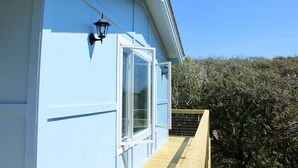 A light blue building with a wooden deck and a window. - Ocean View, large deck, private, nearby beach access  (Pine Knoll Shores)