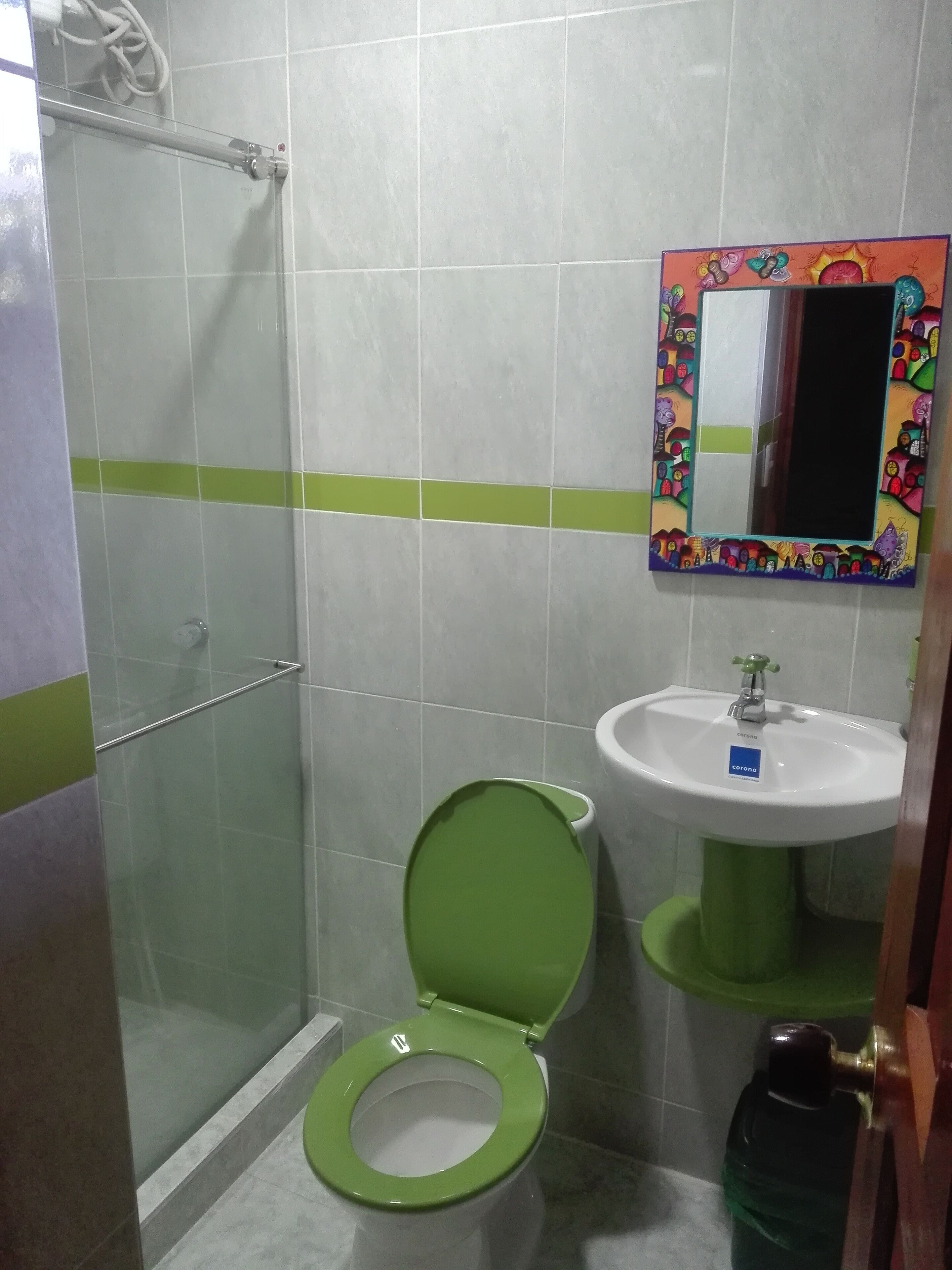 A bathroom with a green toilet, a sink, and a shower area.