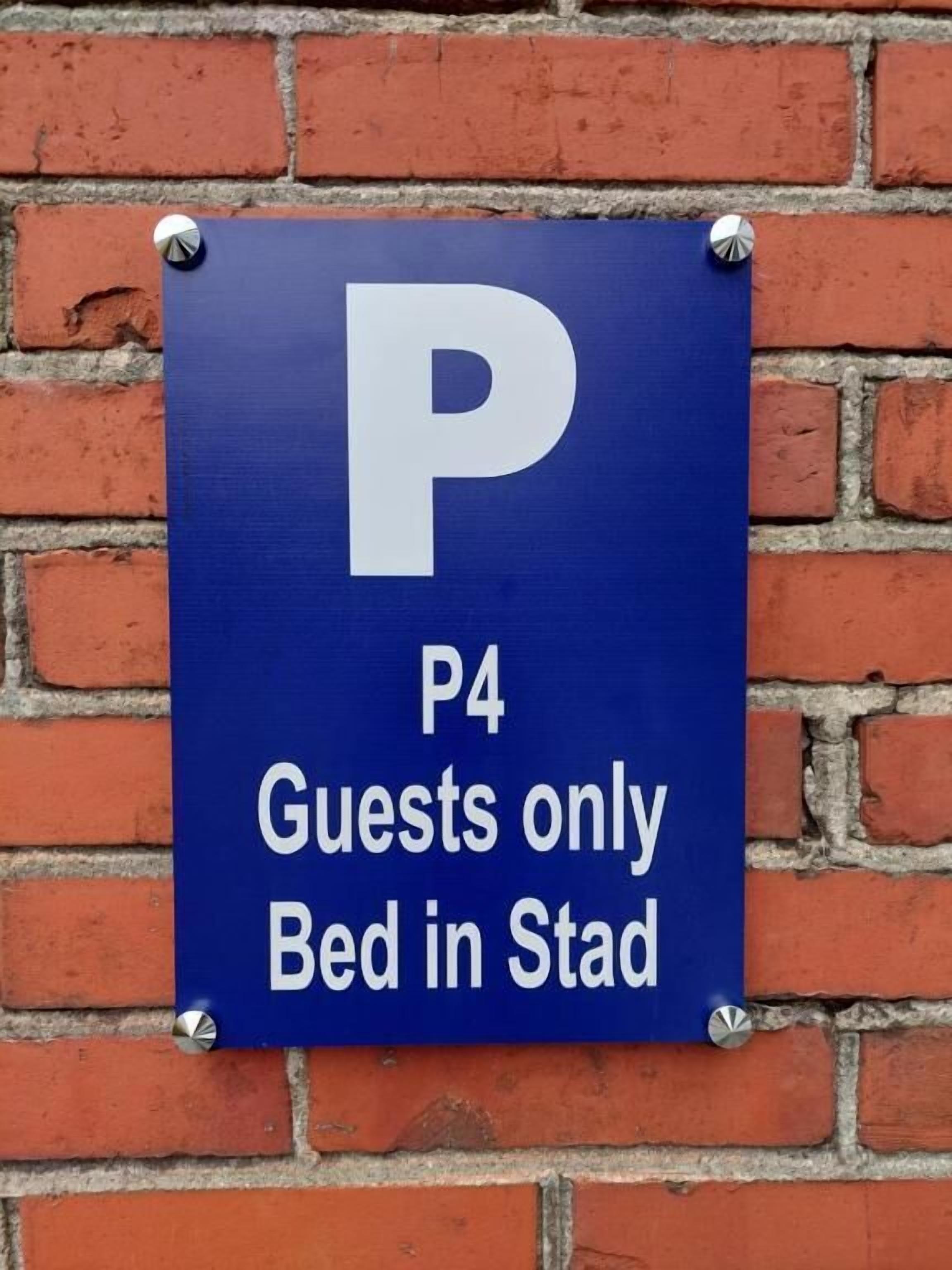 Een blauw bord met een witte 'P' en tekst die aangeeft 'P4 Alleen gasten Bed in Stad'.
