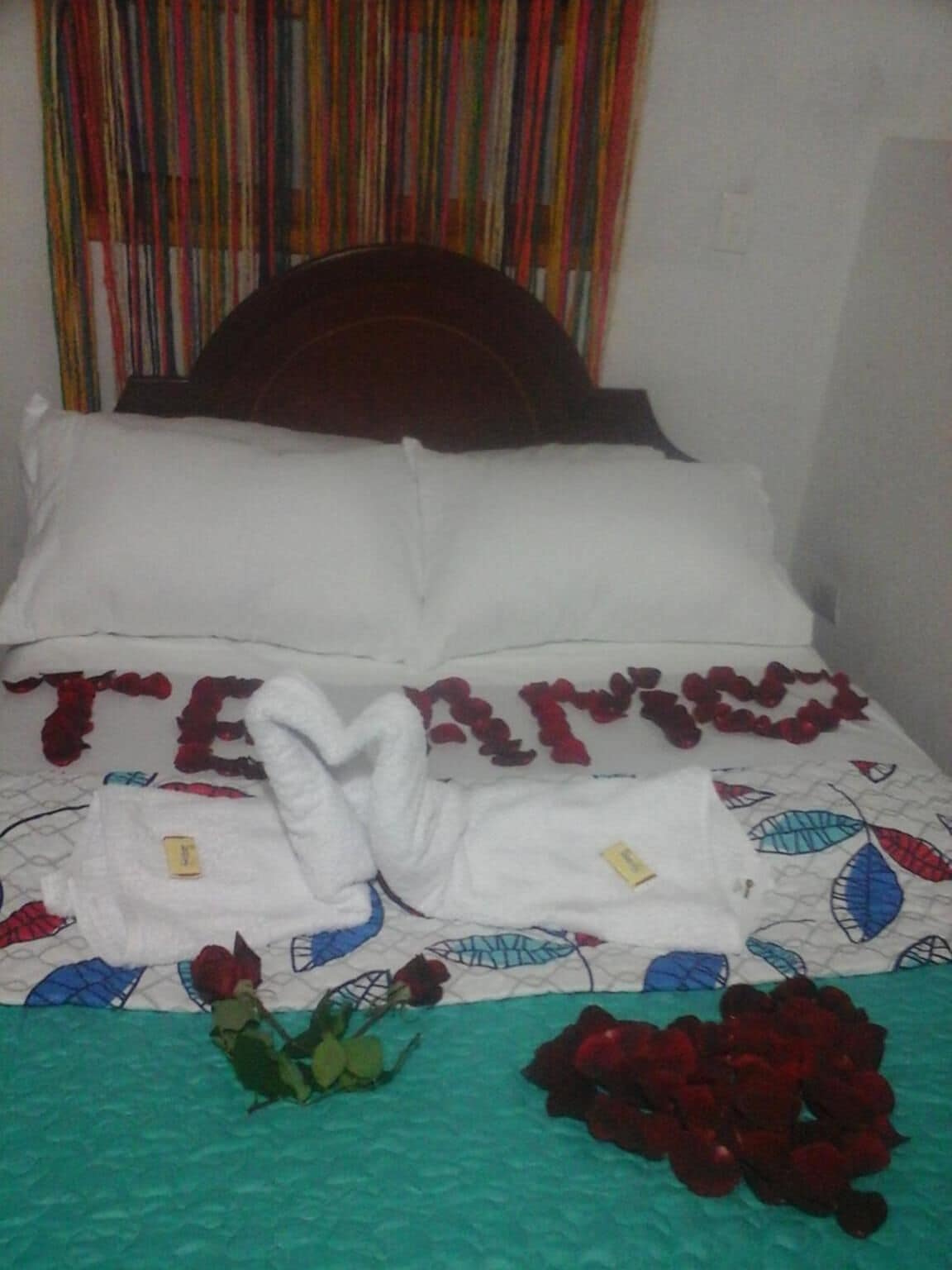 Una cama con almohadas blancas y una colcha estampada con hojas.