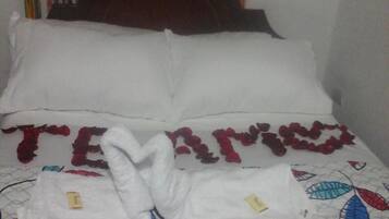 Una cama con almohadas blancas y una colcha estampada con hojas.