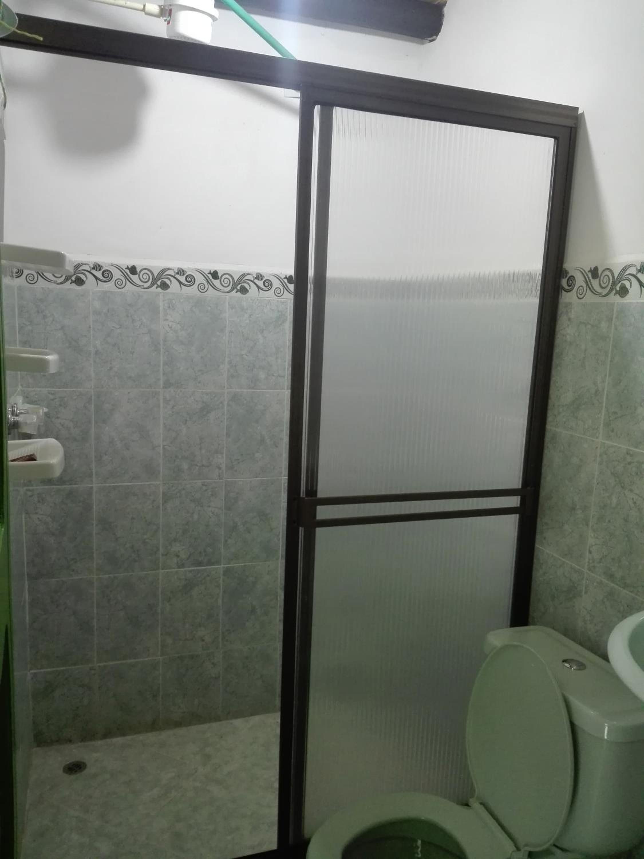 A bathroom with a shower enclosure, a toilet, and a sink.