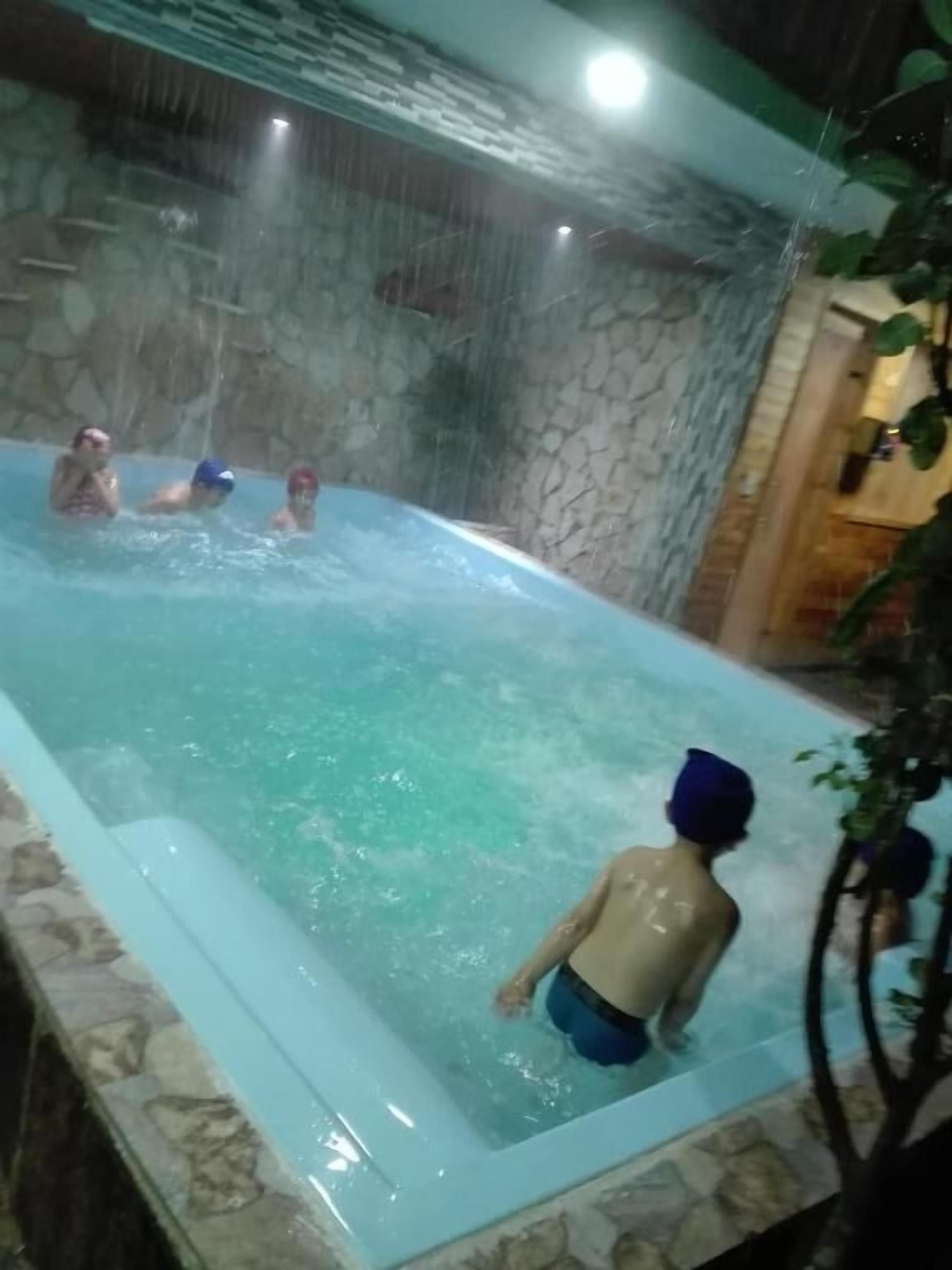 A hot tub with water jets, surrounded by stone walls and a wooden door.
