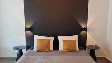 A modern bedroom with a large bed, two bedside tables, and a unique ceiling light fixture.