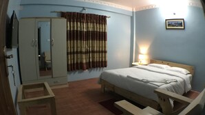 Ein Schlafzimmer mit einem Bett, einer hölzernen Bank, einem Kleiderschrank und einem Vorhang.