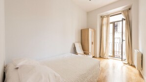 Une chambre à coucher avec un grand lit, une chaise, une armoire et une fenêtre avec des rideaux.