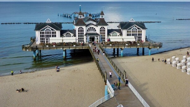 A pier leading to a white building with multiple windows and a central entrance, overlooking a beach and the sea. - Apartment in the beautiful biosphere reserve on Rügen (Lancken-Granitz, Rügen)