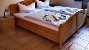 A wooden bed with two pillows and a blanket, a bedside table with a lamp, and a painting on the wall. - Apartment in the beautiful biosphere reserve on Rügen (Lancken-Granitz, Rügen)