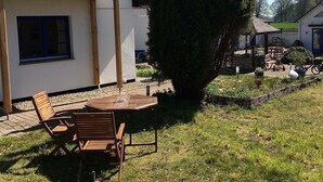 Una casa con balcón, césped y un patio con mesa y sillas.