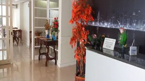 A reception area with a counter, a potted plant, and a cityscape mural on the wall. - Hotel Puçá (Balneário Camboriú)