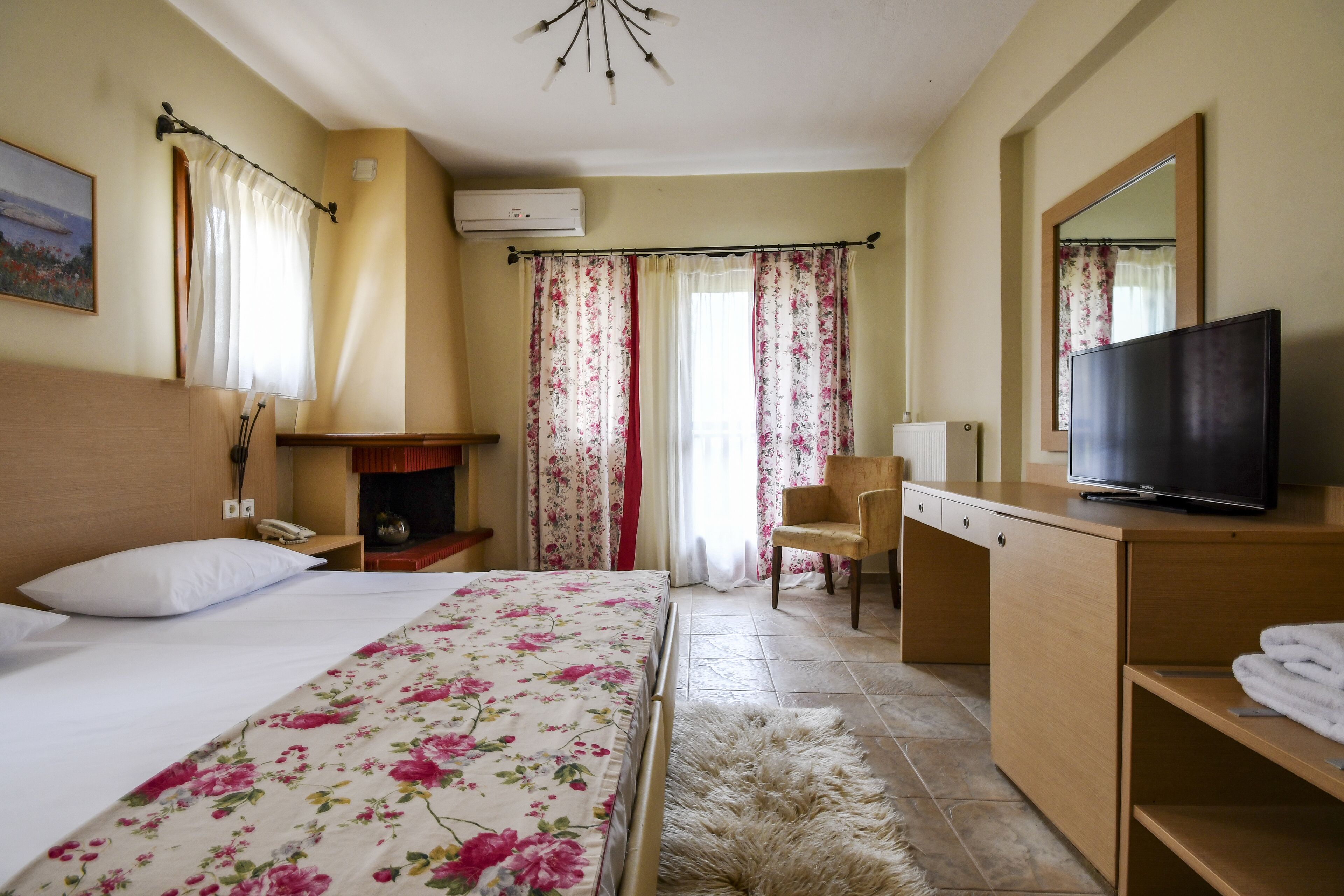 Una habitación de hotel con cama, escritorio, silla, televisión y chimenea.