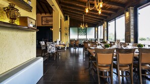 A restaurant with wooden ceilings, large windows, and a variety of seating arrangements including tables and chairs. - Archontiko Liamas (Volvi)