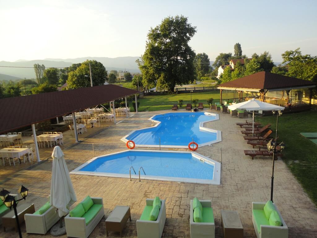 Zona de piscina con sillones reclinables, un área de estar cubierta y vistas al paisaje.