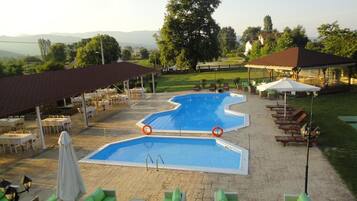 Zona de piscina con sillones reclinables, un área de estar cubierta y vistas al paisaje.