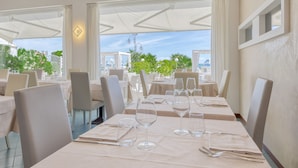 A restaurant with tables set for dining, large windows, and outdoor seating. - Hotel Sanremo (Jesolo)
