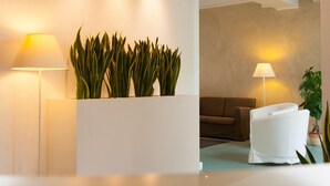 A modern living room with a sofa, a white chair, and two floor lamps. - Hotel Sanremo (Jesolo)