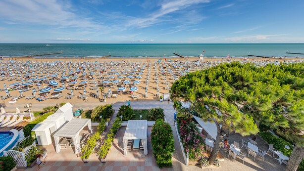 A beach resort with numerous sunbeds and umbrellas, a pool, and a view of the sea. - Hotel Sanremo (Jesolo)