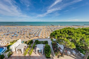 A beach resort with numerous sunbeds and umbrellas, a pool, and a view of the sea. - Hotel Sanremo (Jesolo)