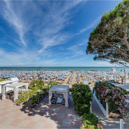 A beachside resort with a terrace, lounge chairs, and a view of the sea.