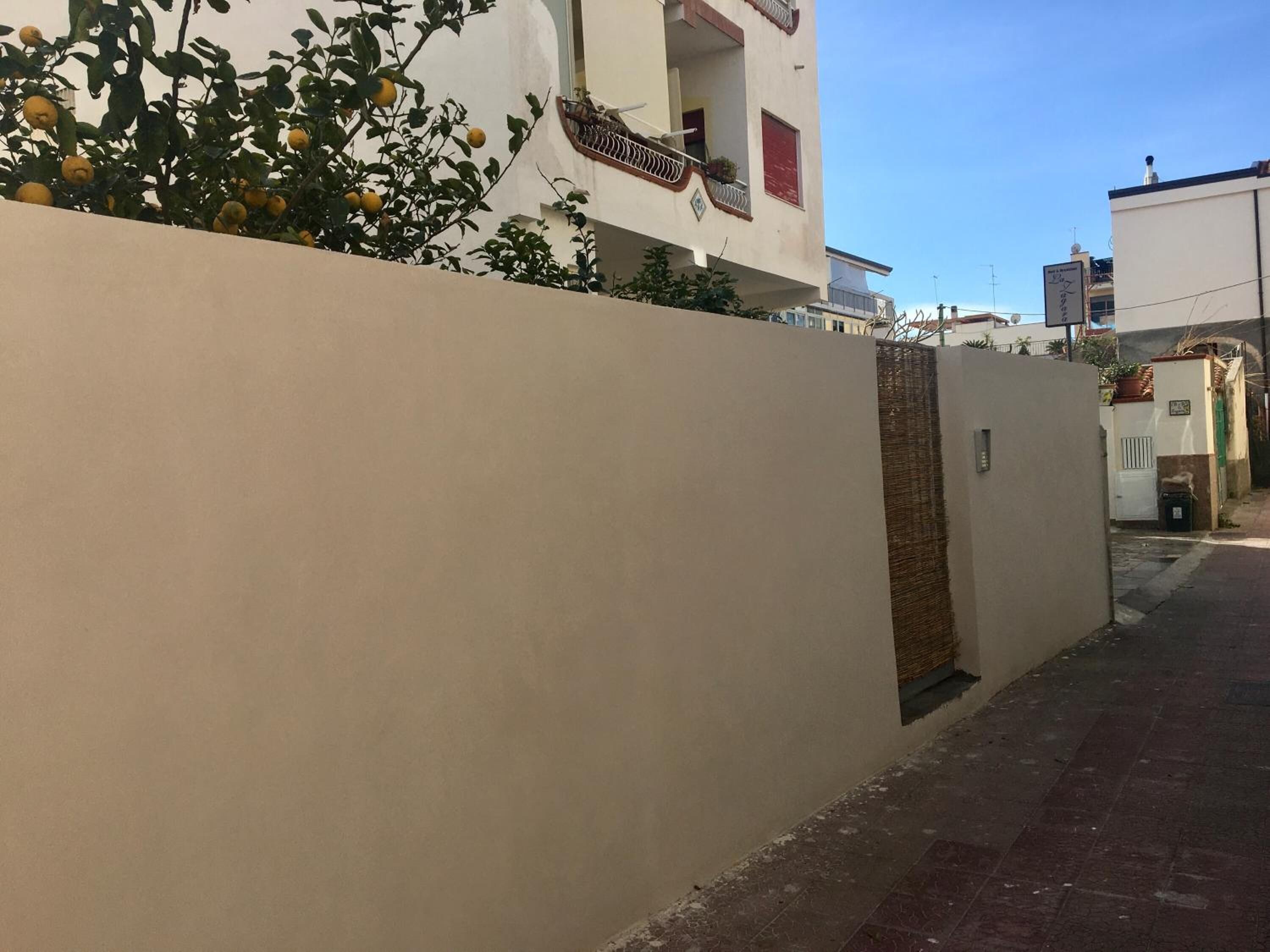 Un vicolo stretto con un muro color crema e un edificio con un balcone.